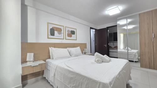 a bedroom with a large white bed and a bathroom at Frente Mar Bessa João Pessoa in João Pessoa