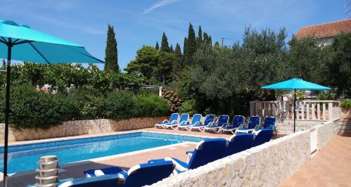 a swimming pool with blue chairs and umbrellas at Apartments Antonio in Cavtat
