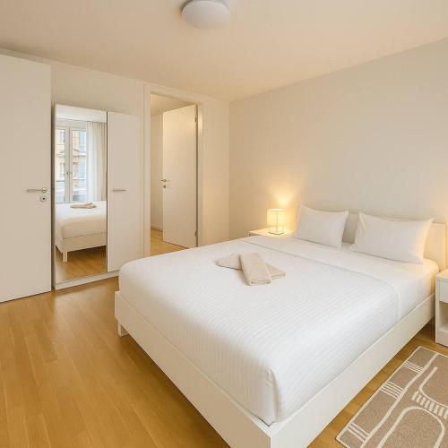 Montchoisi 1 bedroom Near Gare Ouchy Smart Lock في Ouchy: غرفة نوم بيضاء مع سرير أبيض كبير ومرآة