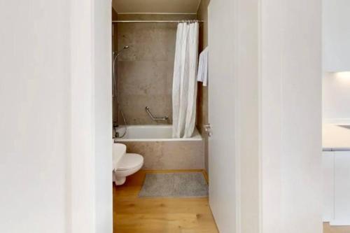 a bathroom with a toilet and a bath tub at The Minimalist free Parking in Lausanne