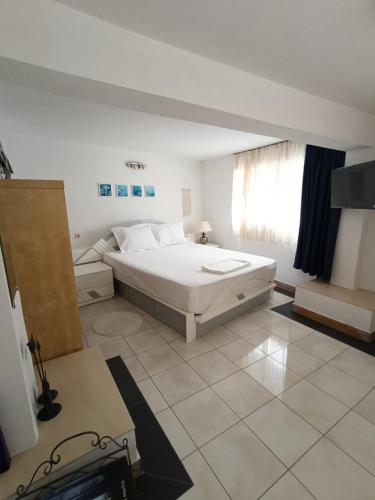 a white bedroom with a bed and a window at Irini Garden House in Vathí