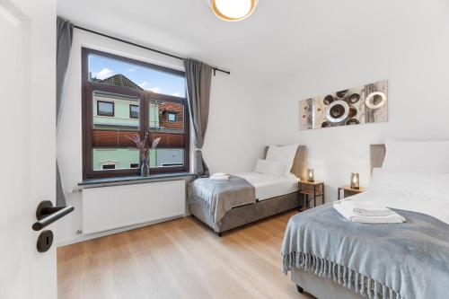 a bedroom with two beds and a large window at Elite Weser Apartments in Bremen