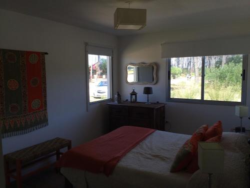 Schlafzimmer mit einem Bett, einem Spiegel und Fenstern in der Unterkunft Nomeolvides Ocean Park Casa in Ocean Park