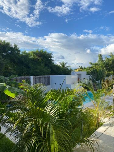 a garden with palm trees and a white fence at Kasa Koh in Brisas de Zicatela