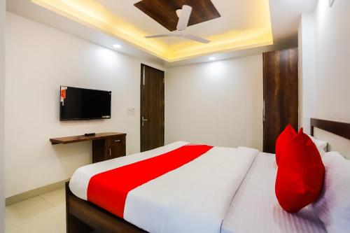 a bedroom with a bed with red pillows and a tv at Super Hotel O Kazhakkoottam Near Technopark Phase 3 in Trivandrum