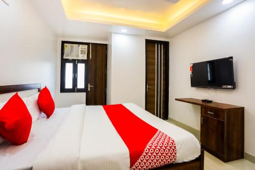 a bedroom with a bed with red pillows and a tv at Super Hotel O Kazhakkoottam Near Technopark Phase 3 in Trivandrum