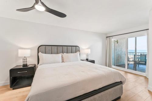 a white bedroom with a bed and a large window at Newly Reno Beachfront Escape I Steps to Beach in Clearwater Beach
