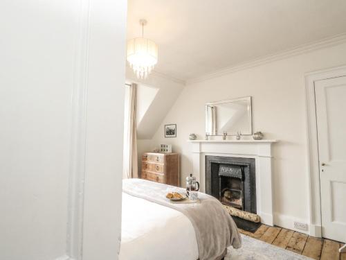 a white room with a bed and a fireplace at Rowan Tree House in Brechin