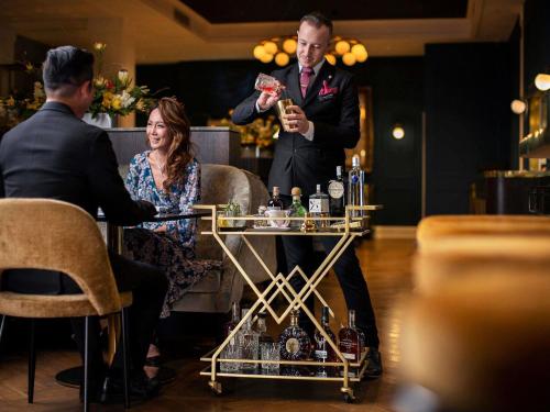 a man and a woman sitting at a table with a drink at Fable Auckland, MGallery in Auckland