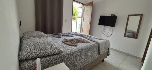 a bedroom with a bed and a mirror and a television at Pousada Coró in São Miguel do Gostoso
