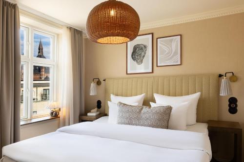 a bedroom with a large white bed and a window at NH Copenhagen Grand Joanne in Copenhagen