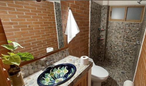 a bathroom with a sink and a toilet and a brick wall at Hotel Johanan in Valle de Bravo