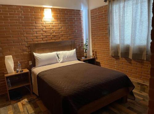 a bedroom with a bed and a brick wall at Hotel Johanan in Valle de Bravo