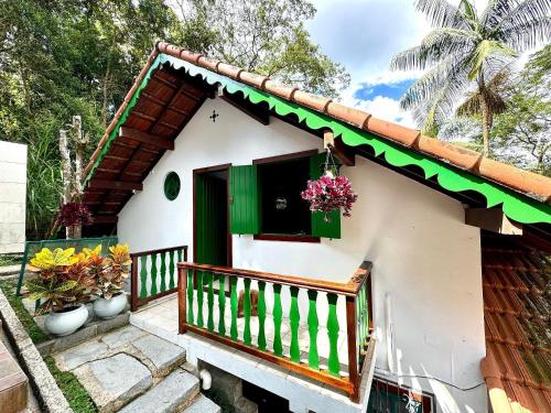een klein huis met een groen raam en een balkon bij Chalé Colonial Aconchegante a 5 Min do Centro in Nova Friburgo
