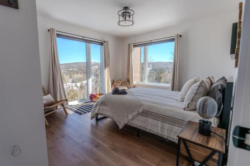 a bedroom with a bed and two large windows at Le Panorama spa lake access in Saint Come