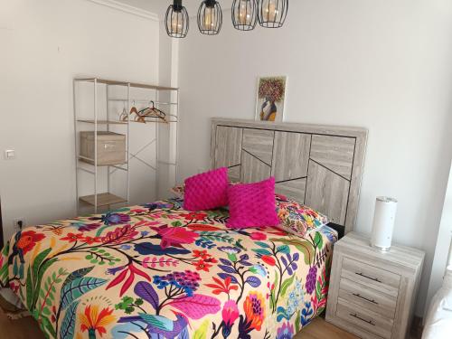 a bedroom with a colorful bed with pink pillows at Dúplex JUNI in Bádames