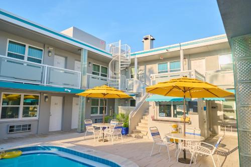 a patio with tables and umbrellas next to a building at Camelot Beach Suites in Clearwater Beach