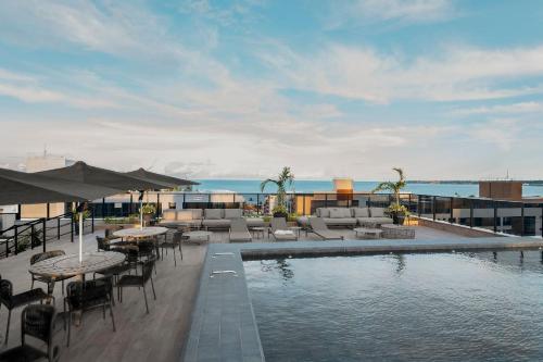 a swimming pool with tables and chairs next to the ocean at WayQ7-Belísismo Flat p/3 pessoas, Tambaú, 200m mar in Tambaú