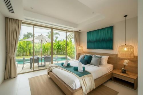 ein Schlafzimmer mit einem großen Bett und einem großen Fenster in der Unterkunft Luxury 3BR Pool Villa near Blue Tree - Bang Tao in Chalong 