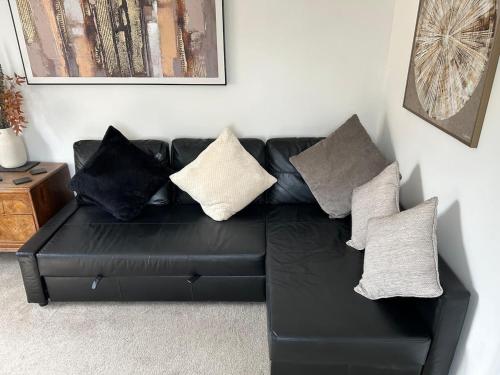 a black leather couch with pillows in a living room at Flat in Filton Mod Rolls Royce gkn in Bristol