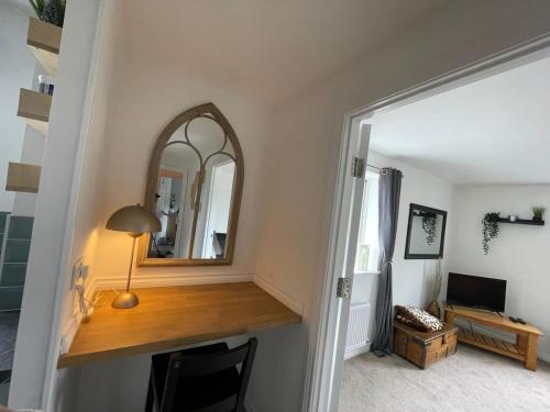 einen Flur mit einem Spiegel und einem Schreibtisch mit einer Lampe in der Unterkunft Flat in Filton Mod Rolls Royce gkn in Bristol
