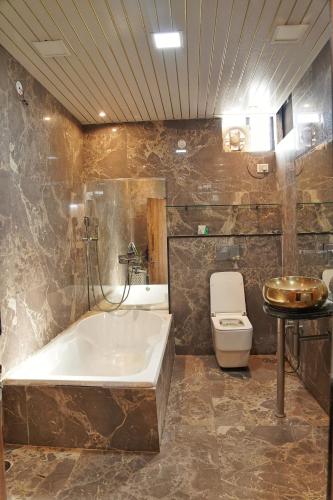 a bathroom with a tub and a toilet and a sink at Nest & Fest in Indore