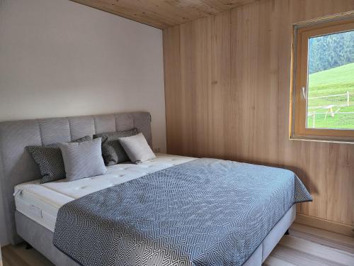 Un dormitorio con una cama grande con ventana. en Blickfang Bregenzerwald, en Langenegg