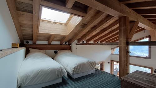 2 bedden in een kamer met houten plafonds bij Chalet Roger in Montvalezan