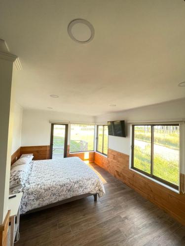 a bedroom with a bed and some windows at Casa Pradera in Frutillar