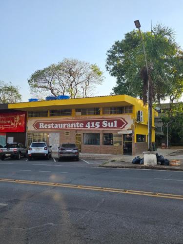 een geel gebouw met auto's geparkeerd op een parkeerplaats bij Kit Osaka in Brasilia
