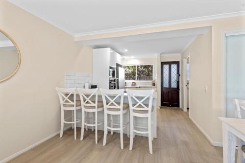 a kitchen and dining room with white stools at Family-Friendly Flat with Balcony Views in Mooloolaba