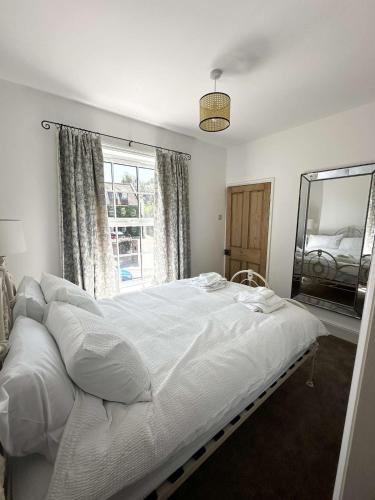 a bedroom with a large white bed and a mirror at Lavender Cottage, Welton in Welton