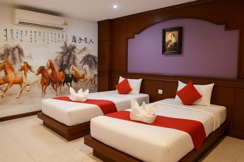 two beds in a room with a painting of horses at Nova Patong in Patong Beach