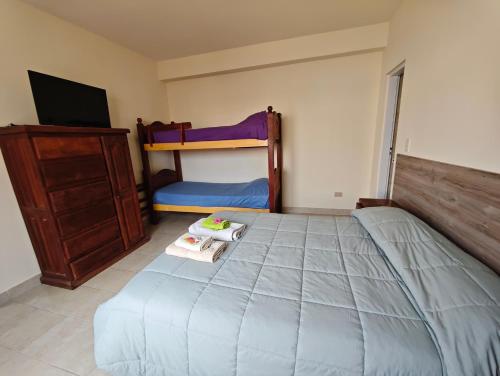 ein Schlafzimmer mit einem Bett, einer Kommode und Etagenbetten in der Unterkunft Keóken a la vuelta del casino in Caleta Olivia