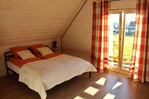 a bedroom with a bed and a large window at Dom Między Wzgórzami in Tylicz
