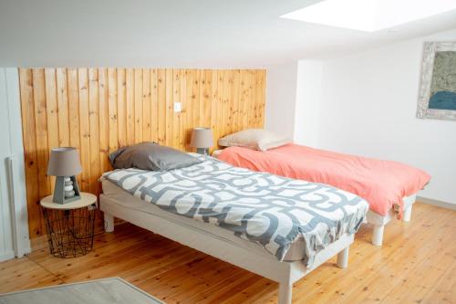 two beds in a room with wooden walls and wood floors at Maison Harmonie entre Ocean et Nature in Saint-Jean-de-Monts