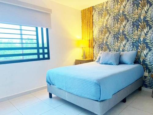 a bedroom with a bed with blue sheets and a window at Departamento Moderno Azul Cielo - 2 Albercas - 3 Min Malecón y Playas in Mazatlán