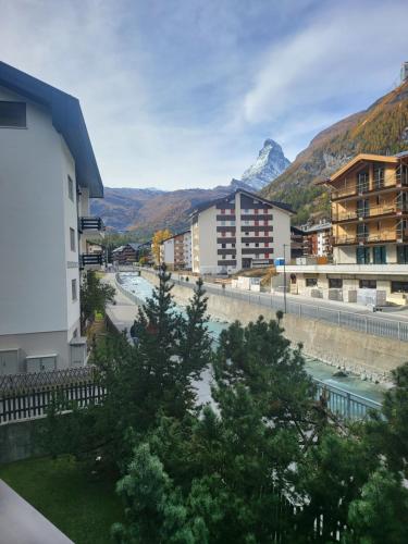 a city with a river and buildings and a mountain at Zermatt Apartment in Zermatt