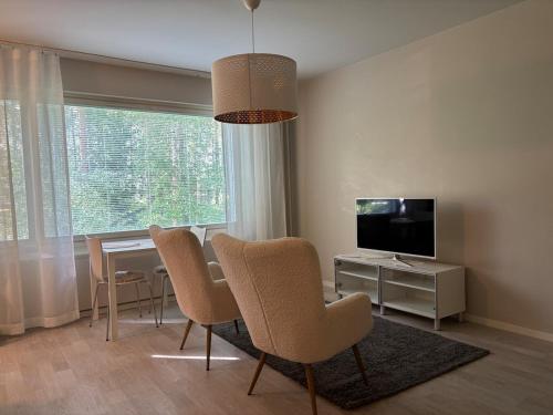 a living room with a table and chairs and a television at Cozy apartment for 2 - free parking in Oulu