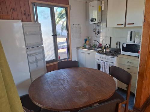 a kitchen with a wooden table and a table and chairs at Cabaña para 6 personas cerca de la playa in Coquimbo