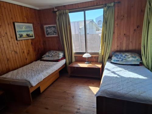 two beds in a room with a window at Cabaña para 6 personas cerca de la playa in Coquimbo