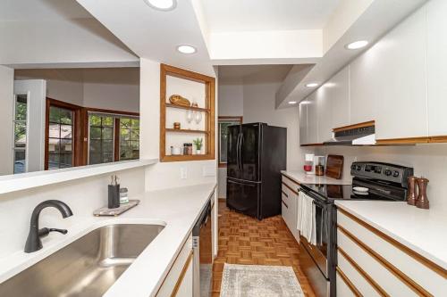 eine Küche mit einer Spüle und einem schwarzen Kühlschrank in der Unterkunft 615 Ash Avenue - Modern Retreat w Hot Tub in Ames