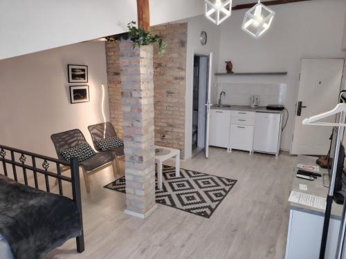 ein Wohnzimmer mit einer Ziegelsäule und eine Küche in der Unterkunft Odličan smeštaj blizu centra in Novi Sad