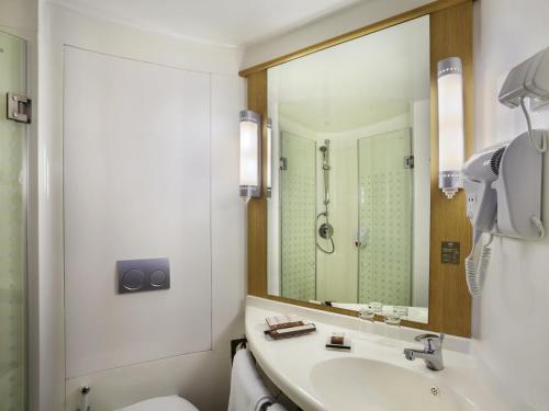 a bathroom with a sink and a toilet and a mirror at ibis Pontianak City Center in Pontianak