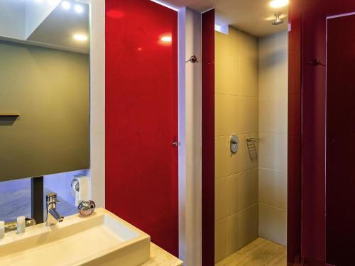 梅里达Ibis Styles Merida Galerias的一间带水槽和红色门淋浴的浴室