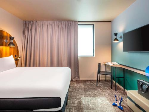a hotel room with a bed and a desk with a television at ibis Styles Paris Meteor Avenue d'Italie in Paris