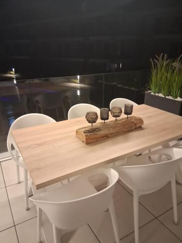 a wooden table with white chairs and a table with cups on it at Sailors' Park Villa Zephir in Nieuwpoort