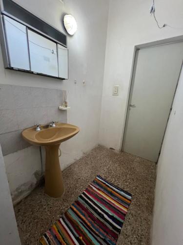 a bathroom with a sink and a mirror and a rug at Depto 168 in Santa Rosa de Calamuchita