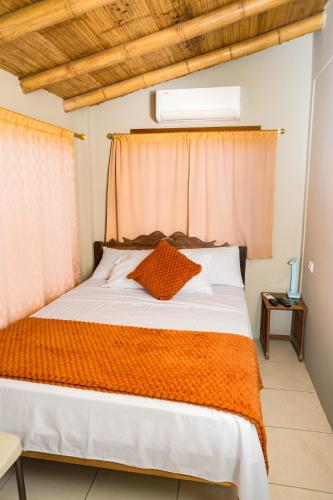 a bedroom with a bed with an orange blanket at La Casa Naranja Hostal in Olón