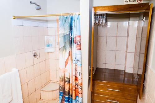 a bathroom with a shower with a toilet and a shower curtain at La Casa Naranja Hostal in Olón